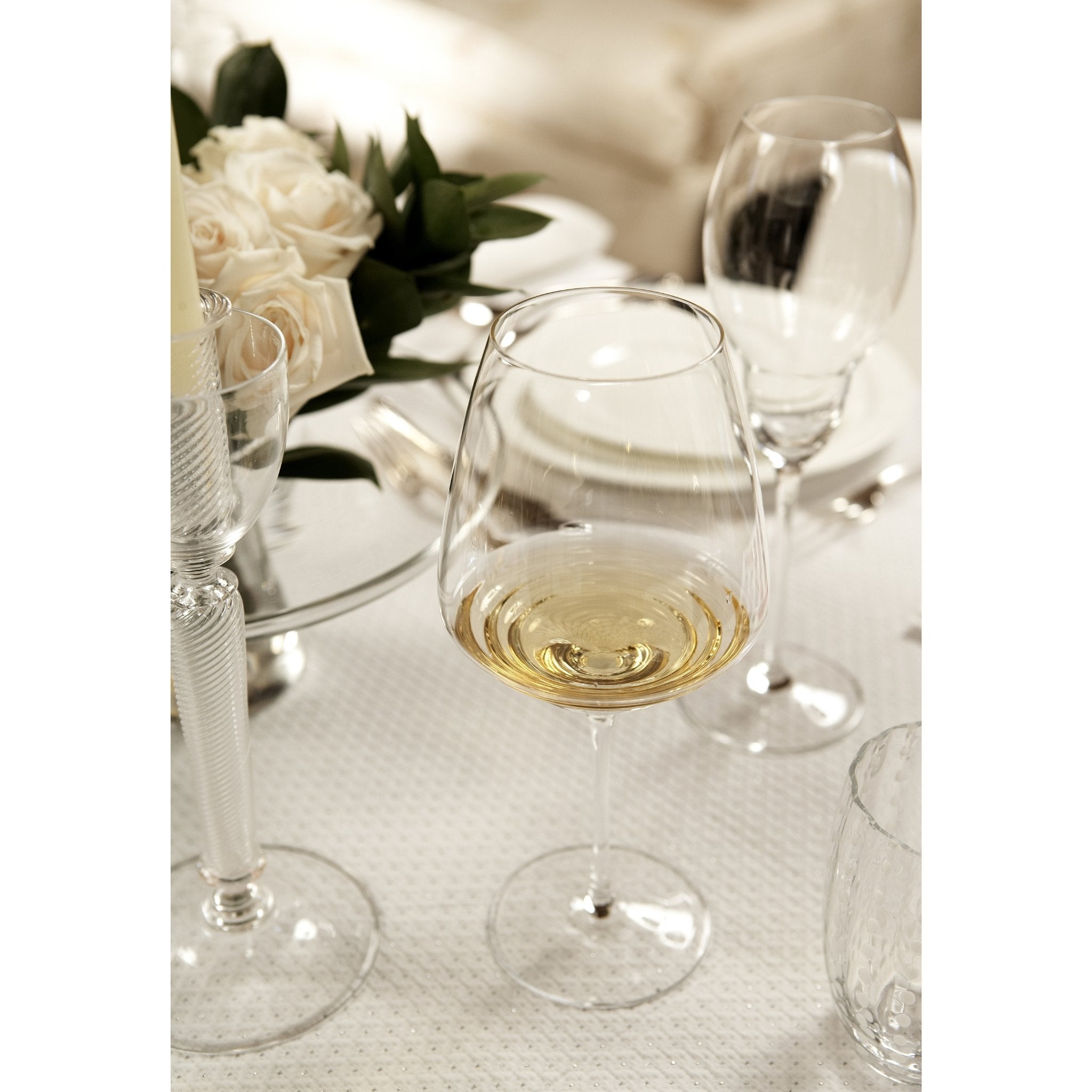 Weißweinglas Farbe transparent mit Wellen im Boden vom Glas mit Weißwein gefüllt auf gedecktem Hochzeitstisch