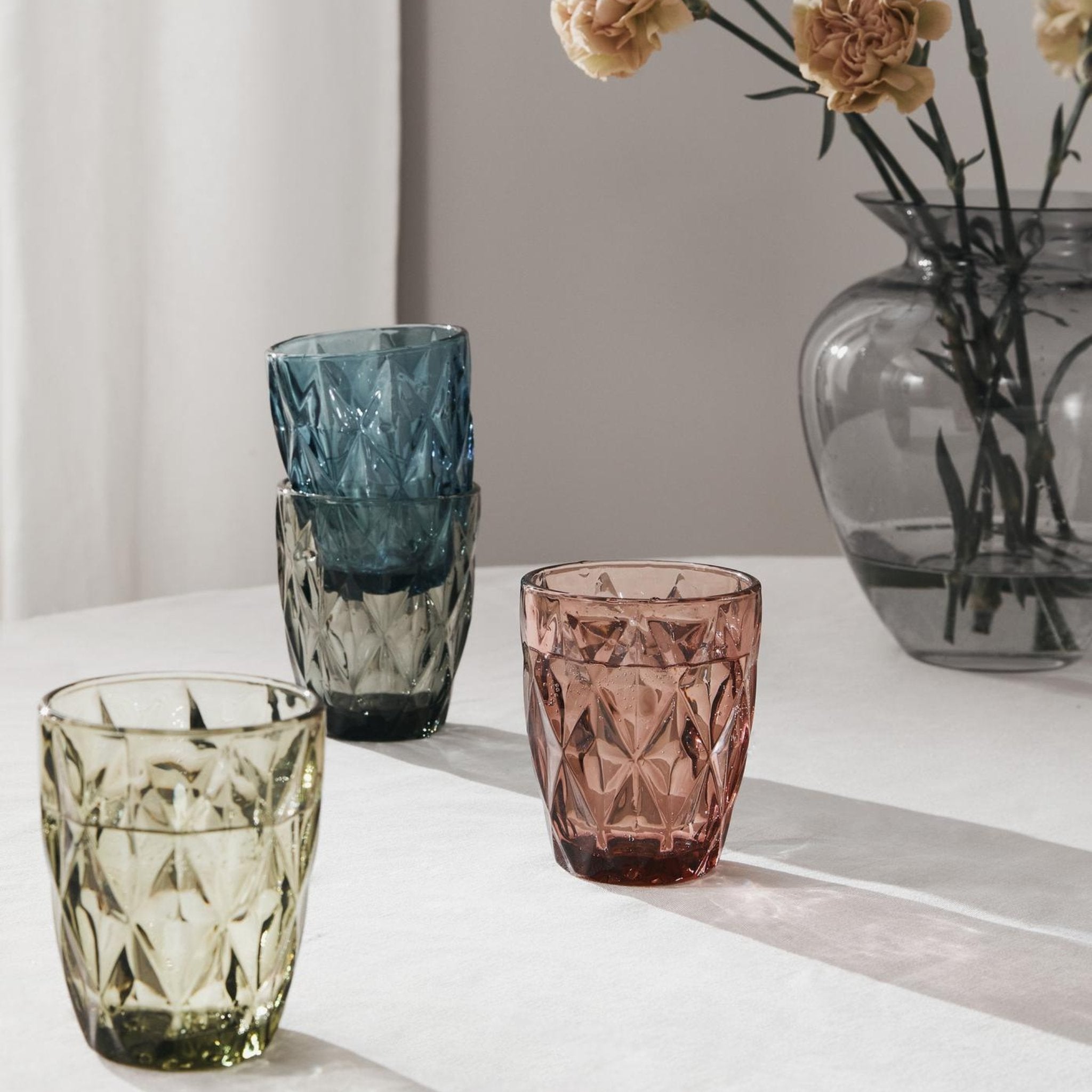 Wassergläser auf Tisch stehend in Farbe grün, türkis, amethyst und blau