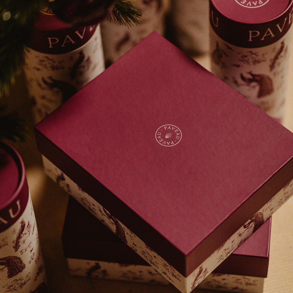 Geschenkbox Paveau mit einer Glasflasche und zwei Trinkgläsern in Farbe Amethyst unter einem Weihnachtsbaum.