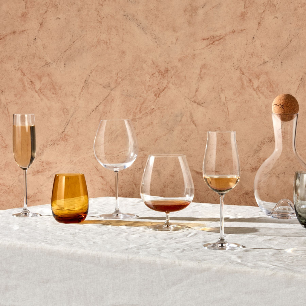 Trinkgläser und Stielgläser in verschiedenen Formen, in transparent, nebeneinander auf Tisch aufgereiht
