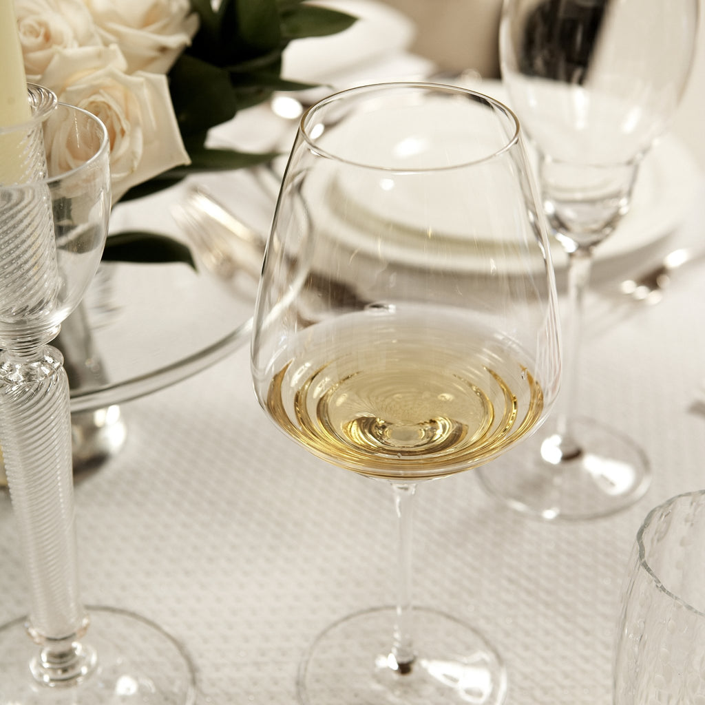 Weißweinglas Farbe transparent mit Wellen im Boden vom Glas mit Weißwein gefüllt auf gedecktem Hochzeitstisch